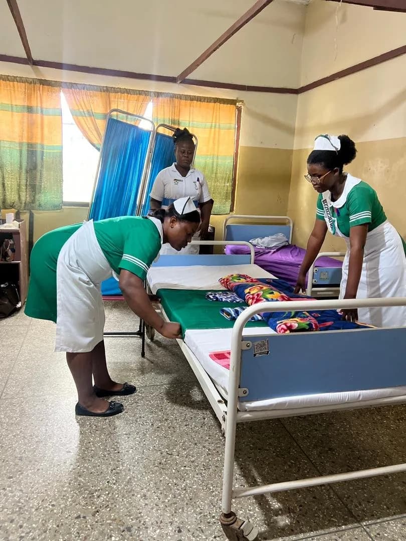 Two final year students demonstrating correct bed-making technique during a practical ward assessment