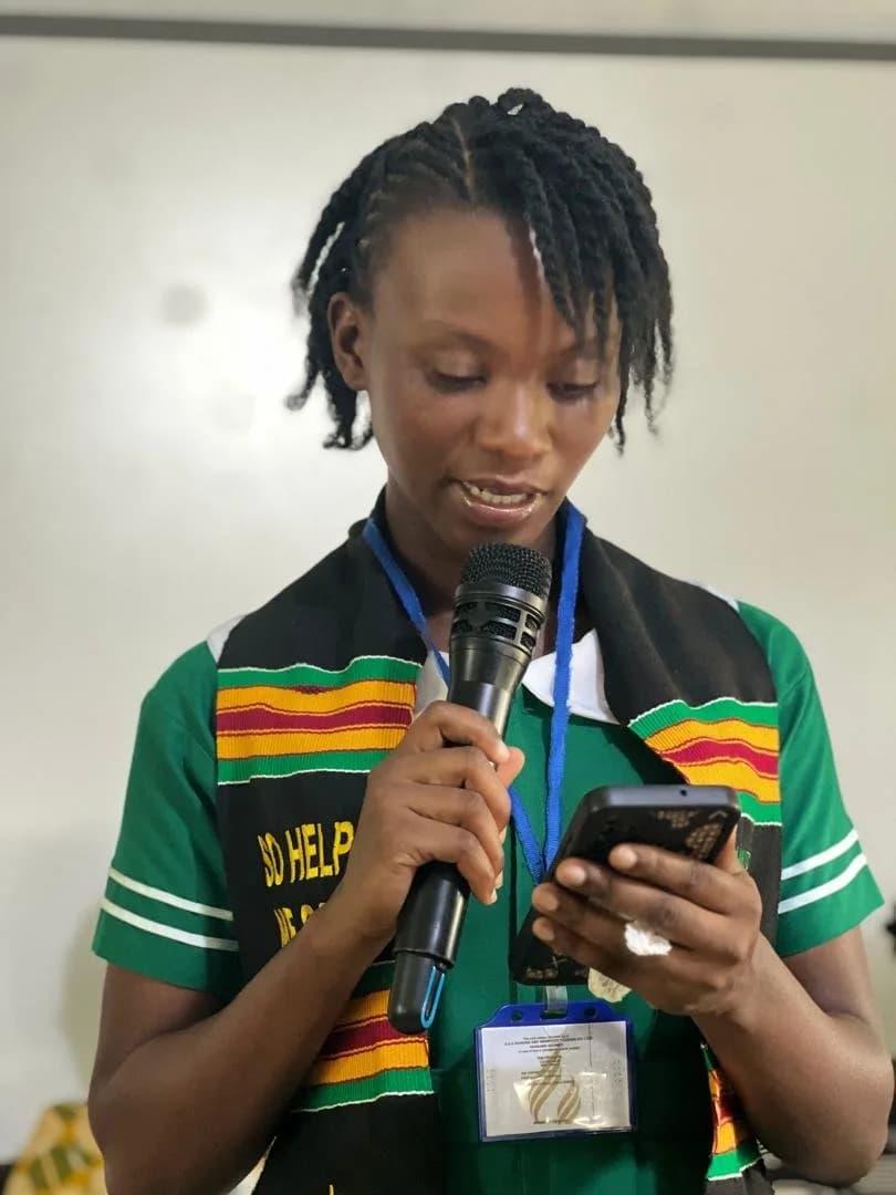 Female student speaking at microphone during SRC handover ceremony holding phone and reading from notes