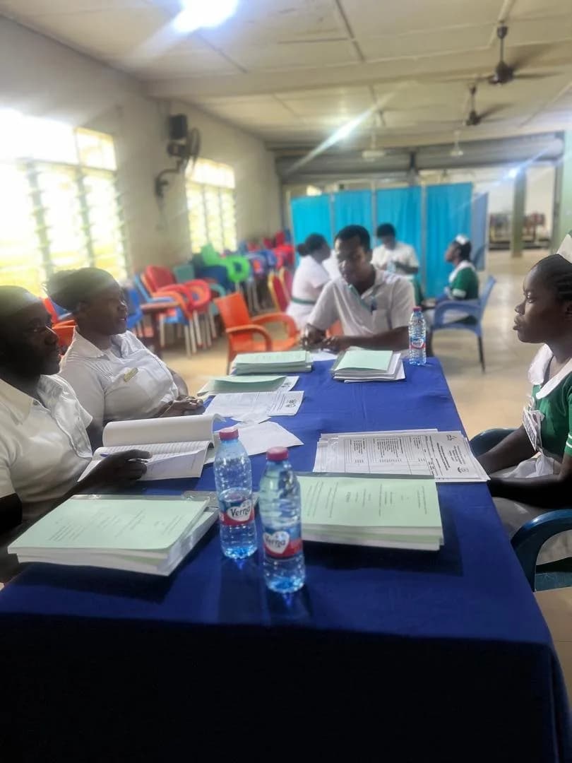 Examiners seated at a blue-draped table interviewing a student nurse during the viva
