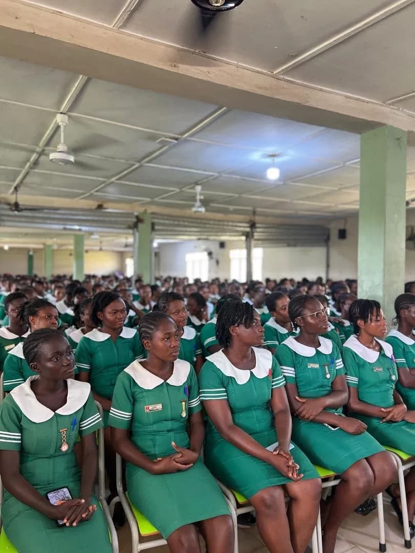Two female students in green nursing uniforms embracing and celebrating during handover ceremony