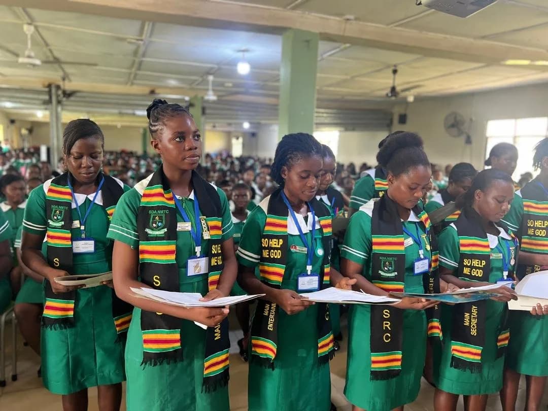 Multiple female students in green nursing uniforms with colorful scarves during SRC handover ceremony assembly