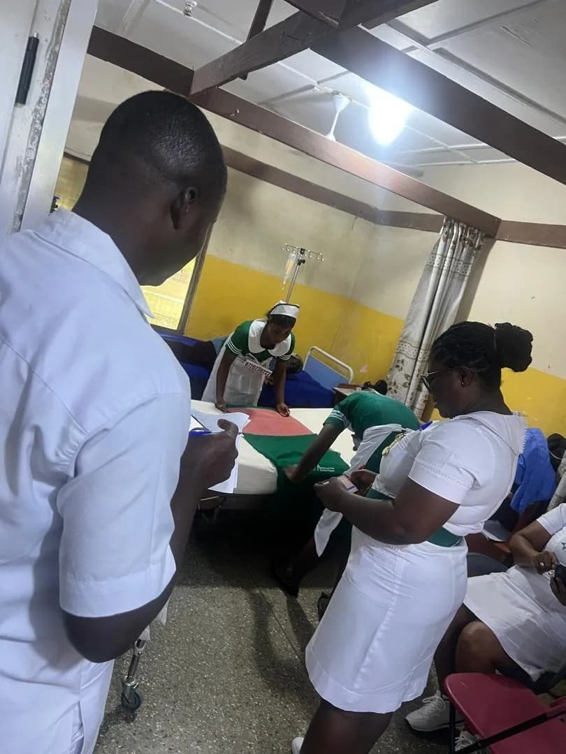 Examiners observing and scoring students as they carry out a bedside practical station